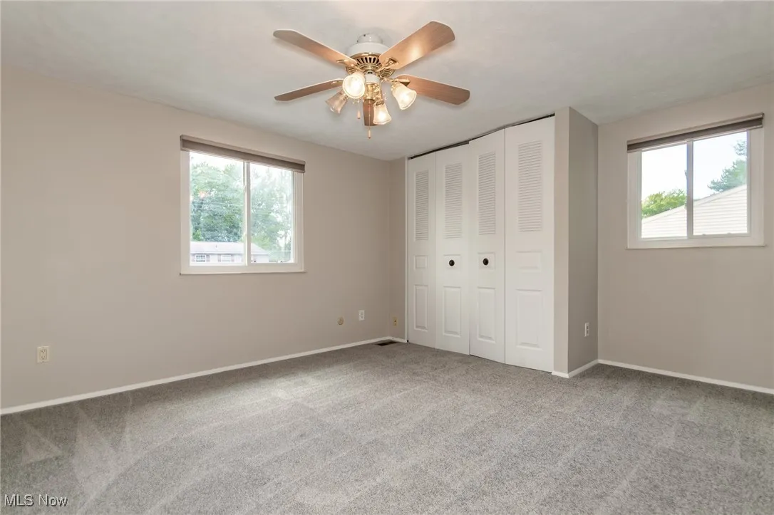 Unfurnished bedroom featuring light carpet, multiple windows, and a closet