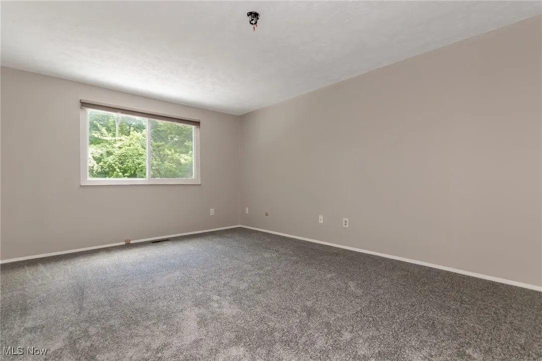 Carpeted spare room featuring baseboards