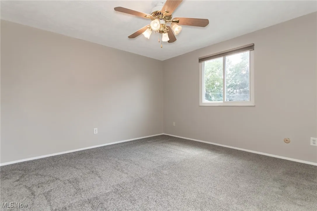 Carpeted empty room with baseboards and ceiling fan