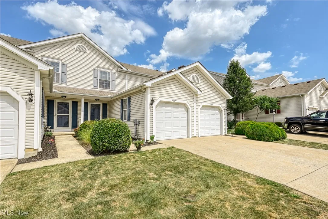 Traditional-style home with a garage, a porch, driveway, and a front lawn