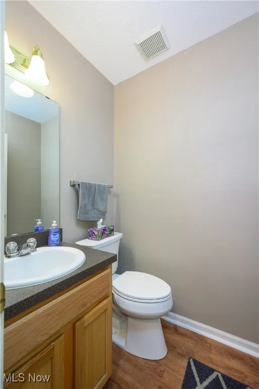 Half bathroom with wood finished floors and vanity