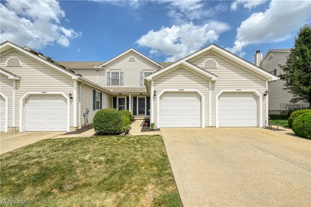 Traditional home featuring concrete driveway, covered porch, a front yard, and a garage