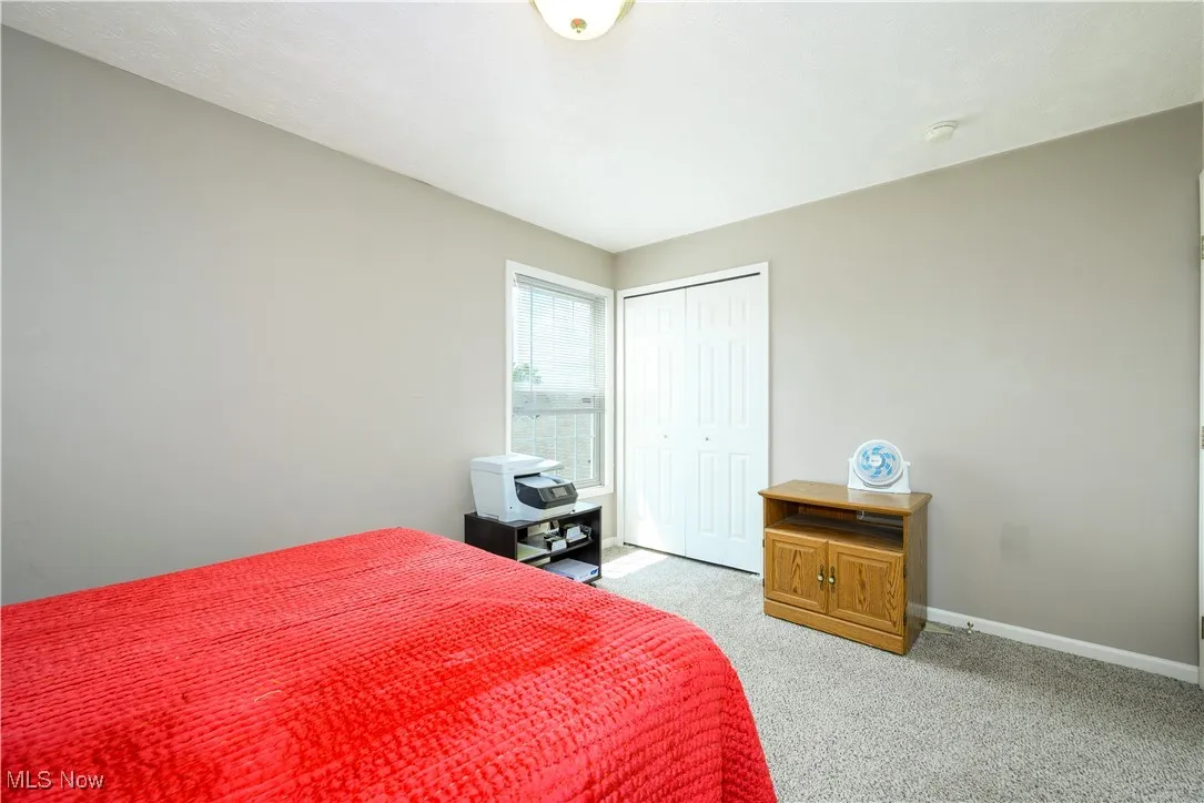Bedroom with light colored carpet and a closet