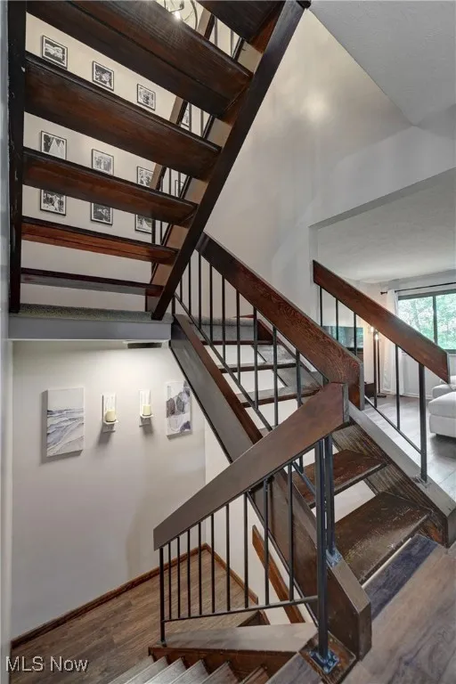 Staircase with wood finished floors and a high ceiling