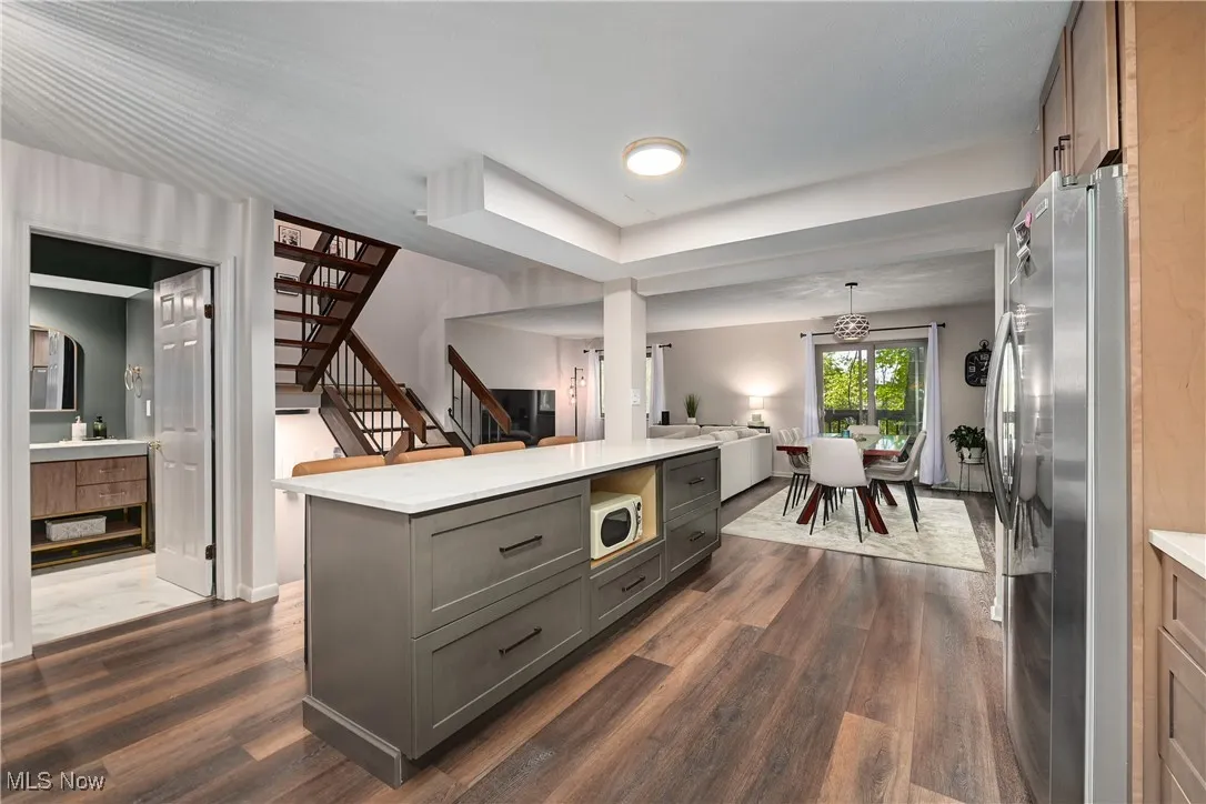 Kitchen featuring gray cabinets, freestanding refrigerator, dark wood-style flooring, and decorative light fixtures