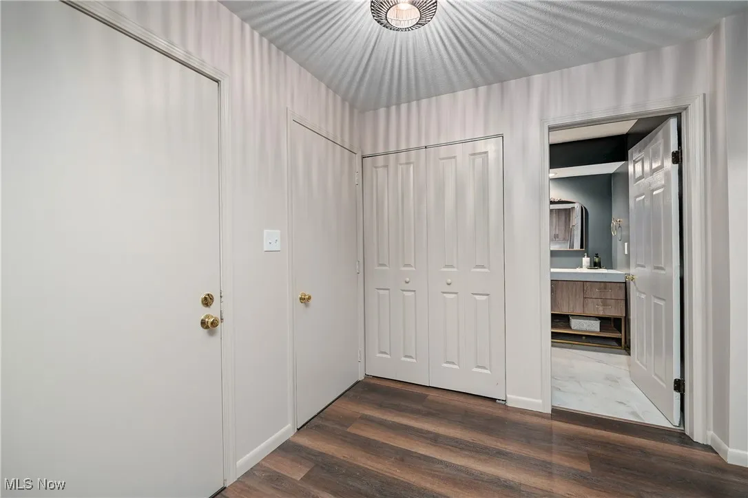 Hall featuring dark wood-style flooring and baseboards