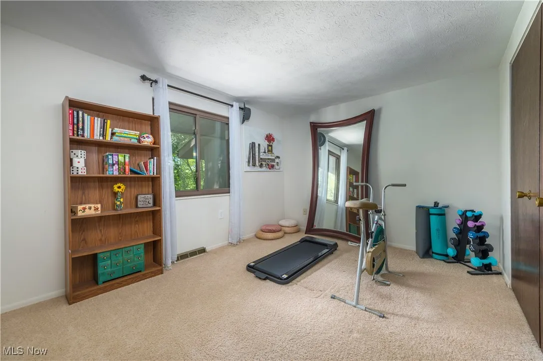 Exercise room with a textured ceiling and light carpet
