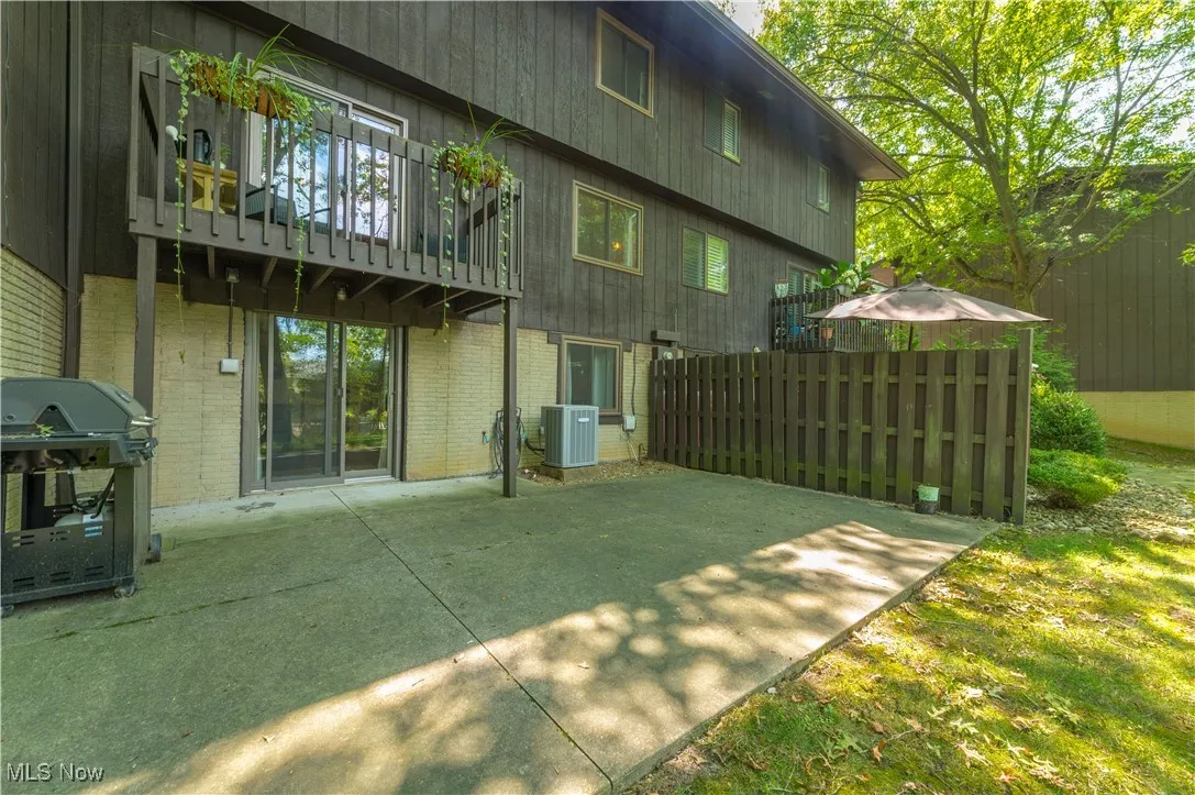 Rear view of property featuring a balcony, a patio area, and brick siding
