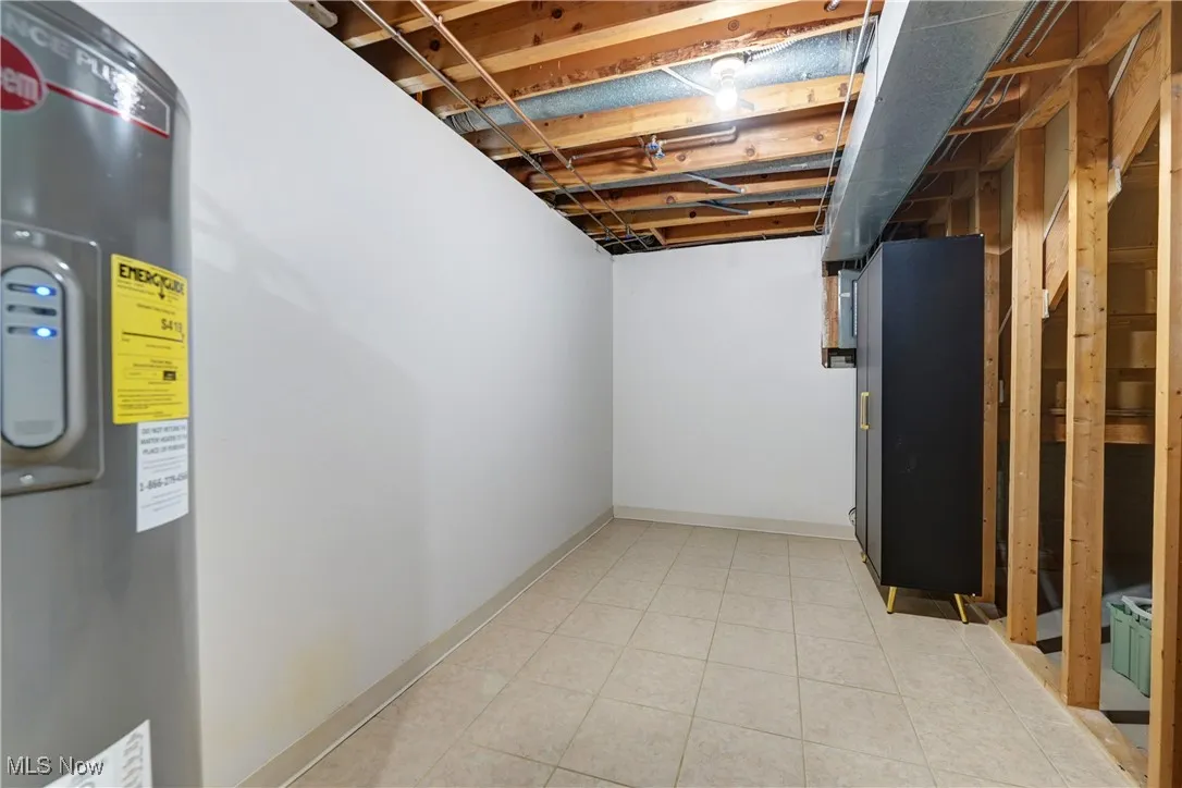 Below grade area featuring water heater and light tile patterned floors
