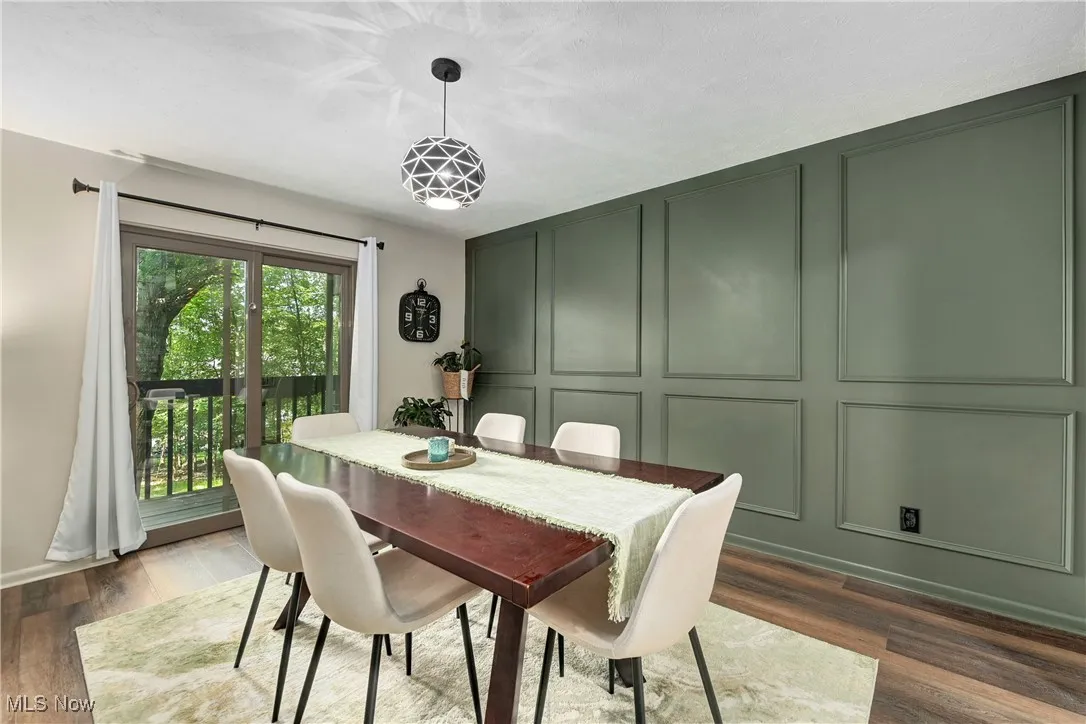 Dining space featuring a decorative wall and dark wood-style flooring