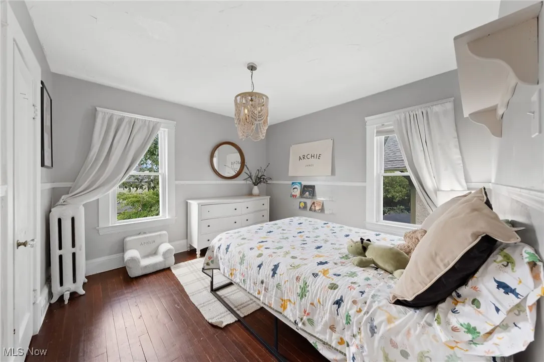 Bedroom featuring radiator, dark wood-style flooring, and a chandelier