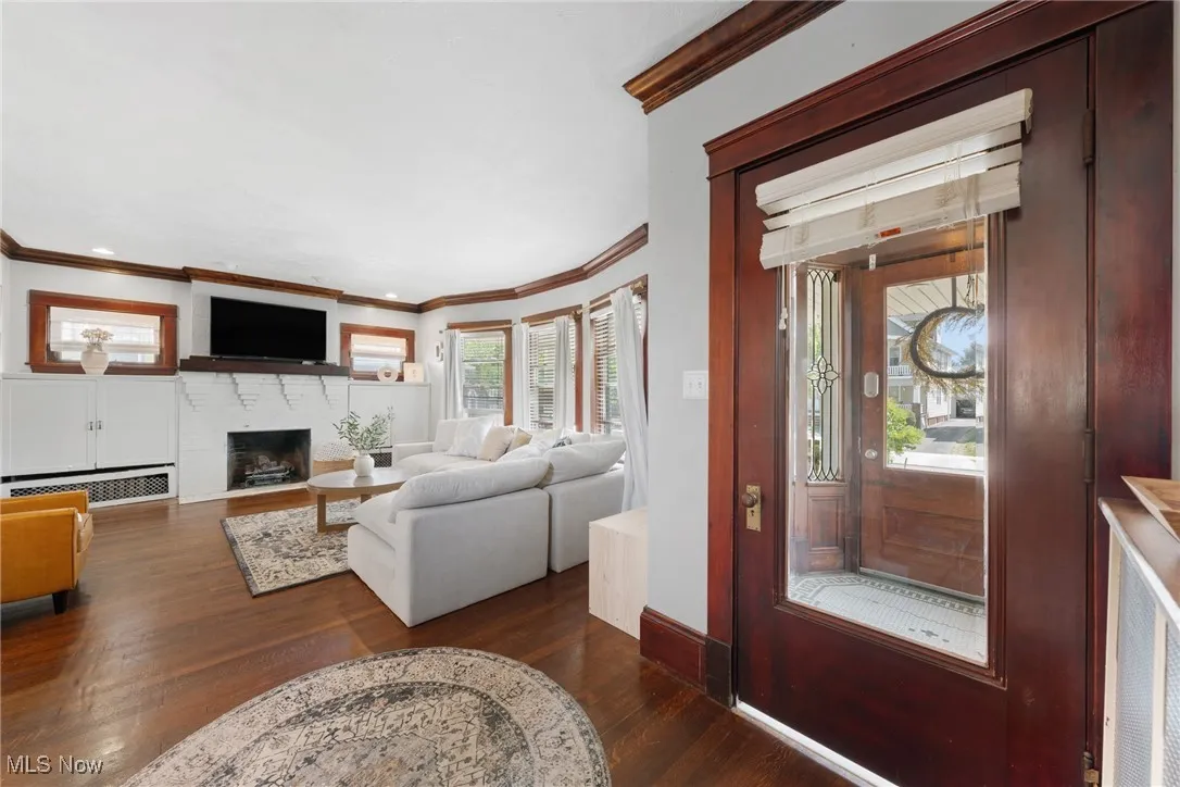 Living area featuring crown molding, dark wood finished floors, and a fireplace