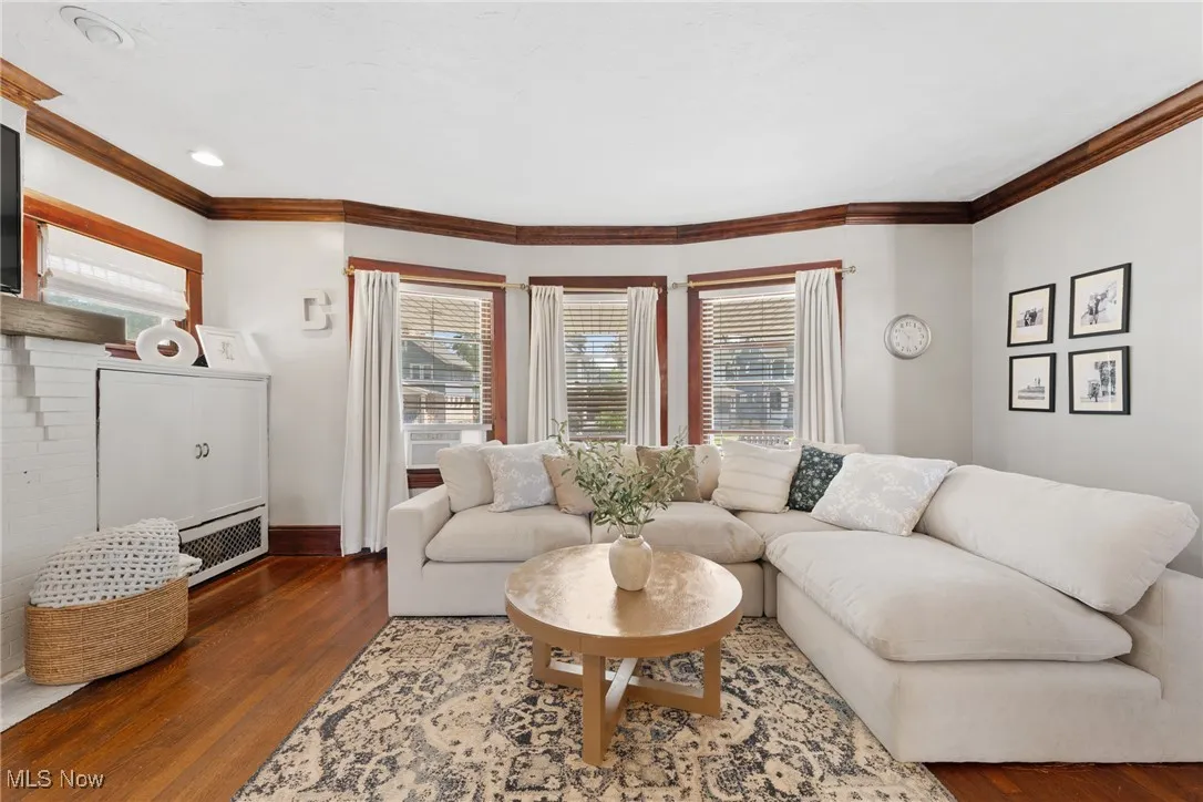 Living area with wood finished floors and ornamental molding