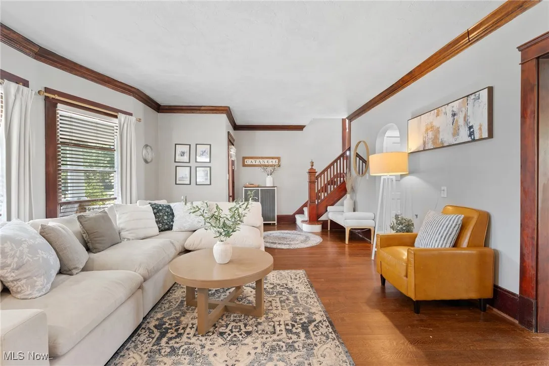Living area with ornamental molding, wood finished floors, and stairway