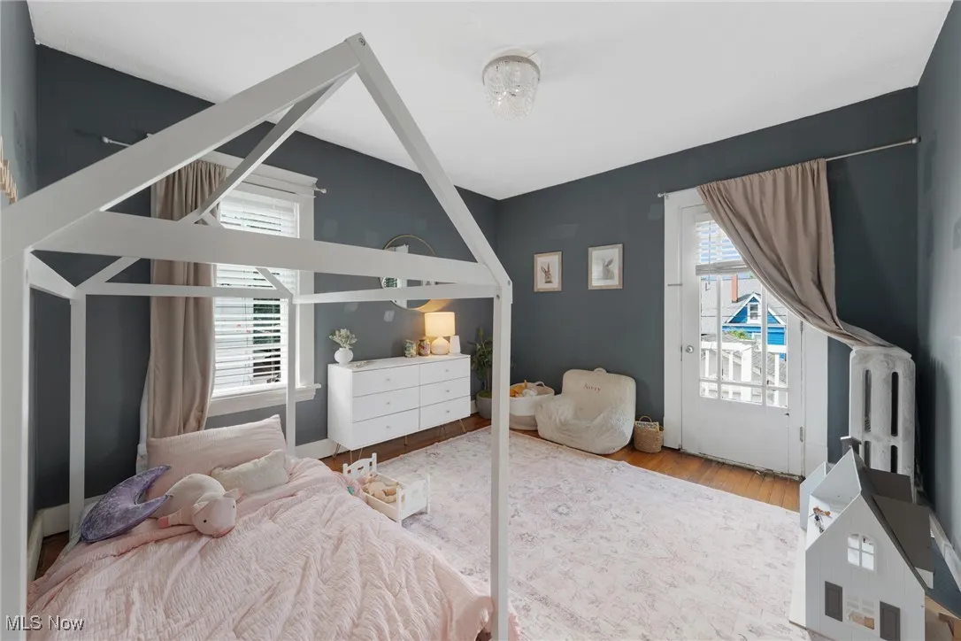 Bedroom with multiple windows, access to outside, and wood finished floors