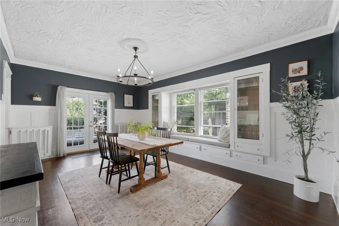 Dining area featuring wainscoting, plenty of natural light, a decorative wall, crown molding, and a textured ceiling