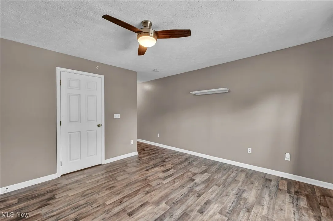 Spare room with a textured ceiling, light wood-style floors, and ceiling fan