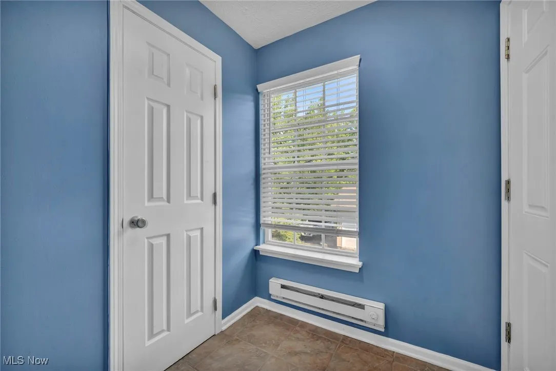 Doorway with a baseboard radiator, tile patterned flooring, and a textured ceiling