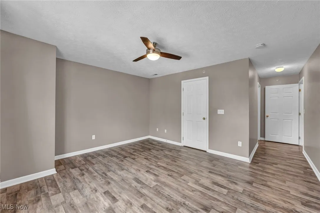 Unfurnished bedroom with a textured ceiling, light wood-type flooring, and ceiling fan