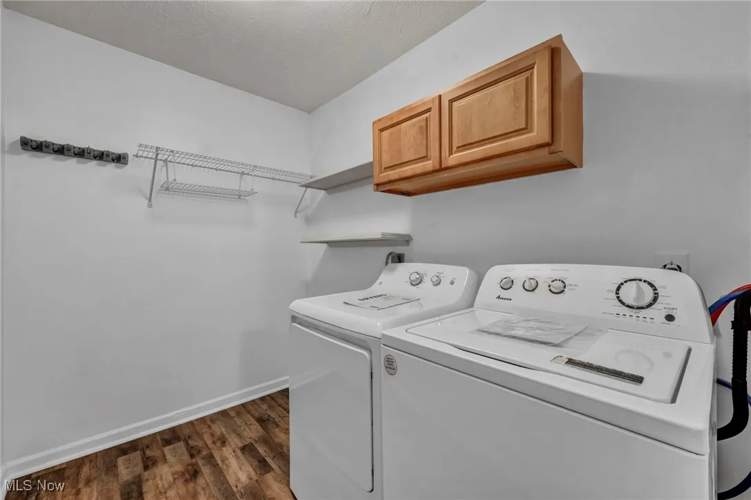 Washroom featuring dark wood finished floors, cabinet space, independent washer and dryer, and a textured ceiling