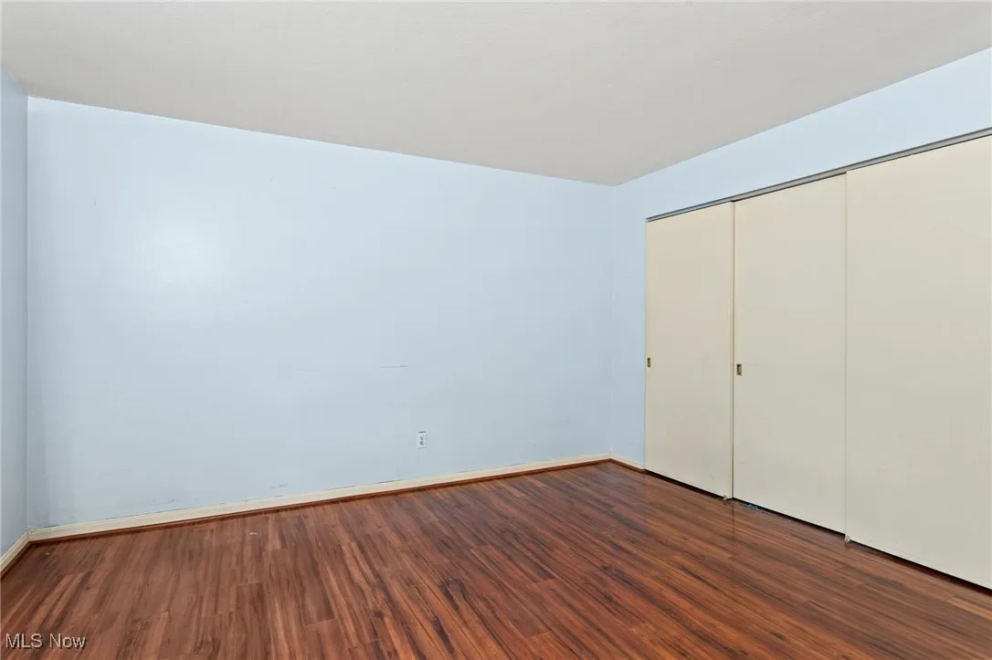Unfurnished bedroom featuring dark wood-style flooring and a closet
