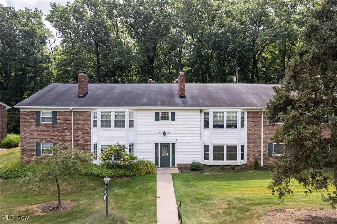 View of front of home featuring a chimney, brick siding, and a front yard