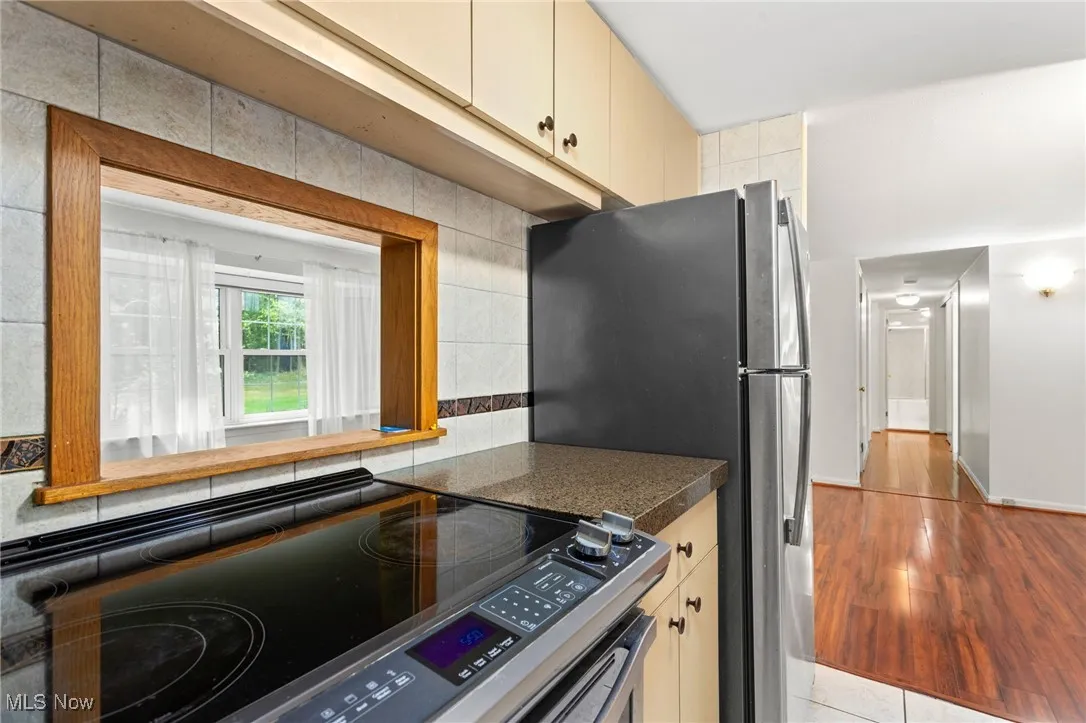 Kitchen with stainless steel electric range, dark countertops, cream cabinets