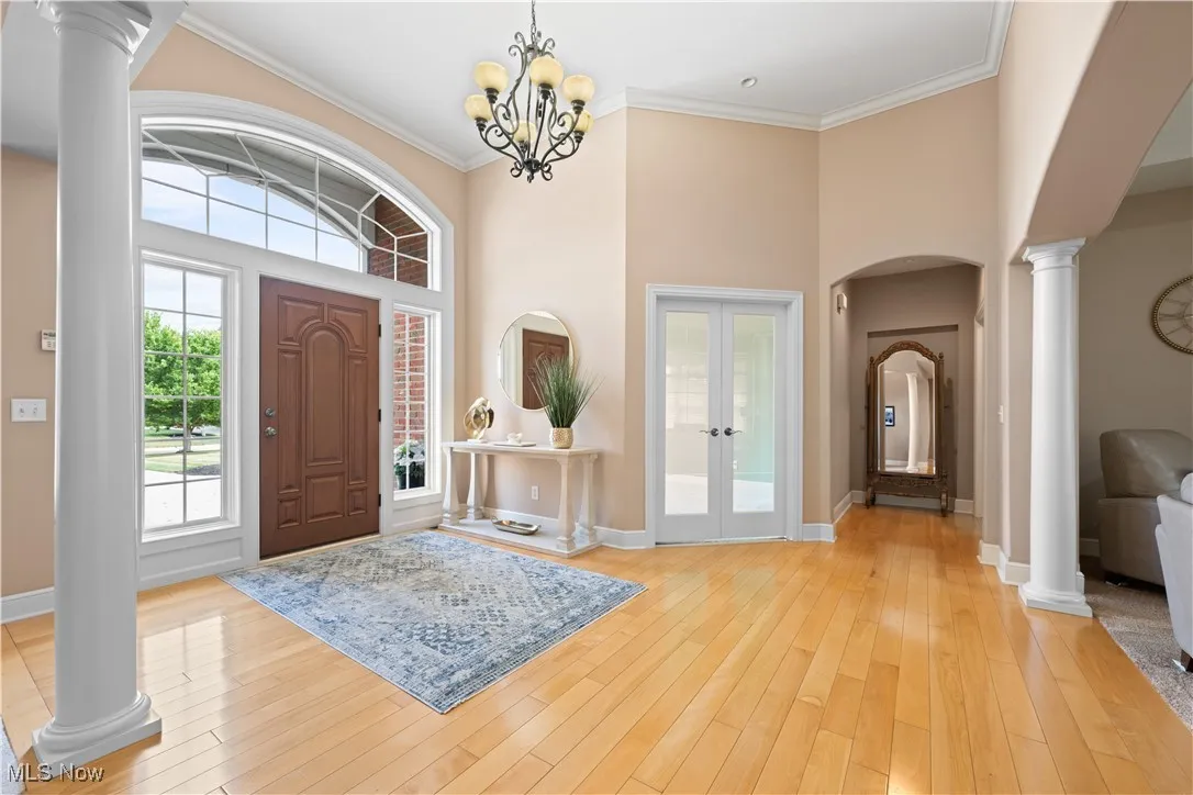 Foyer entrance featuring ornate columns, crown molding, french doors, a high ceiling, and arched walkways