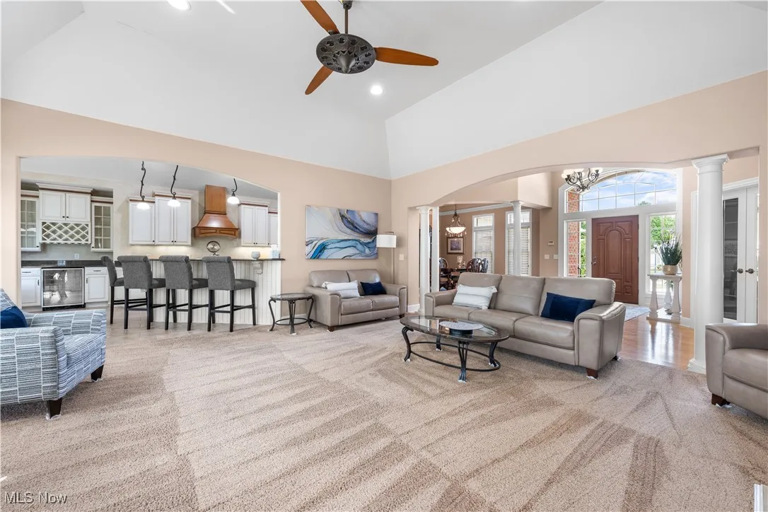Living area featuring high vaulted ceiling, arched walkways, ornate columns, a chandelier, and recessed lighting