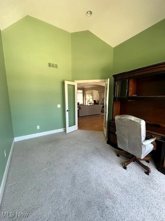 Office with carpet flooring, high vaulted ceiling, and french doors
