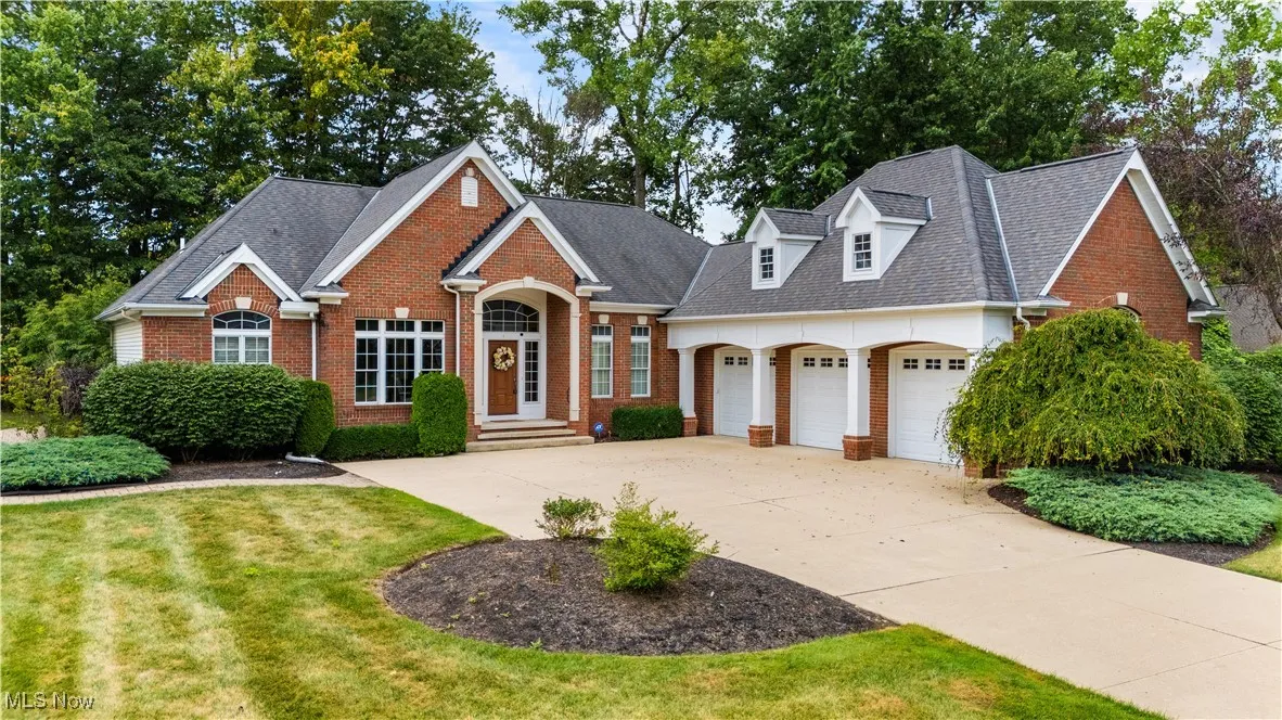 View of front of house featuring brick siding, a shingled roof, concrete driveway, an attached garage, and a front lawn