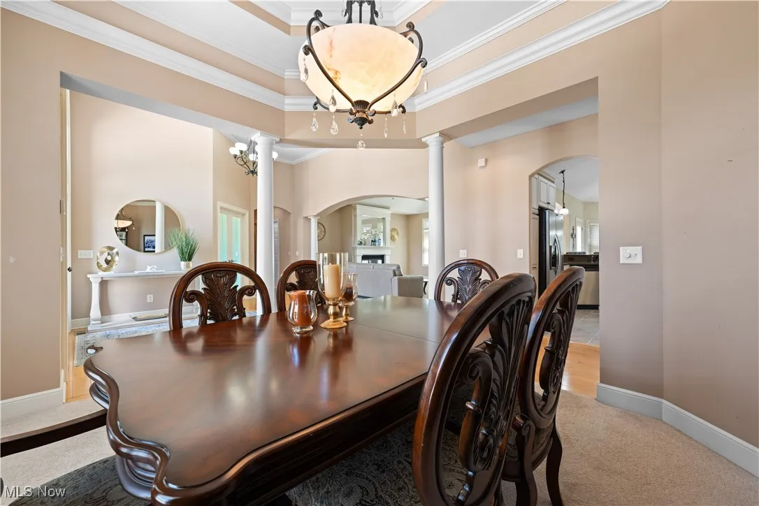 Dining area with light carpet, ornamental molding, a chandelier, and arched walkways