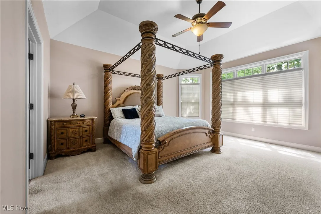 Carpeted bedroom with ceiling fan and lofted ceiling