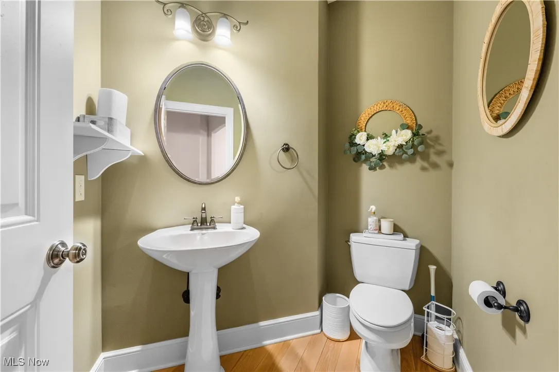 Half bath with wood finished floors and baseboards