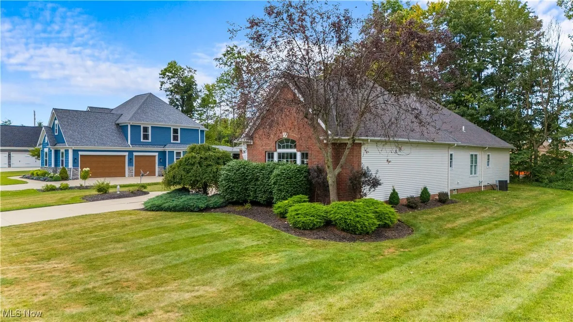 View of side of property with a lawn and roof with shingles