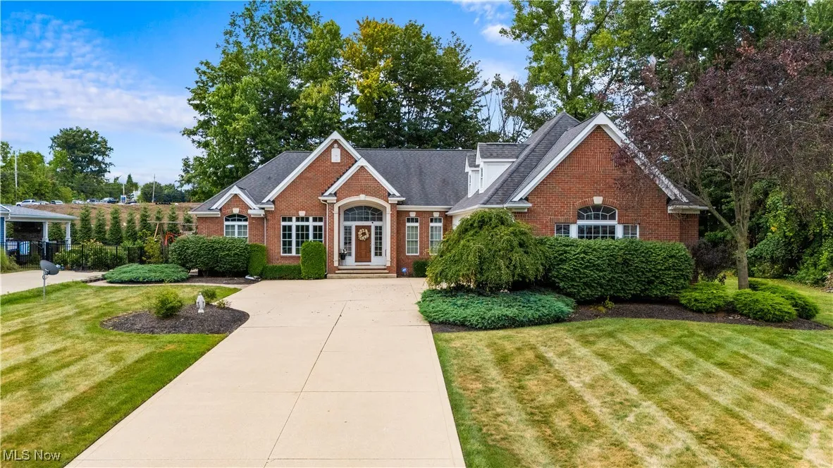 View of front of house with brick siding, a front lawn, concrete driveway, and roof with shingles