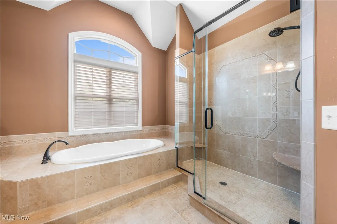 Full bath featuring a bath, a shower stall, tile patterned flooring, and lofted ceiling
