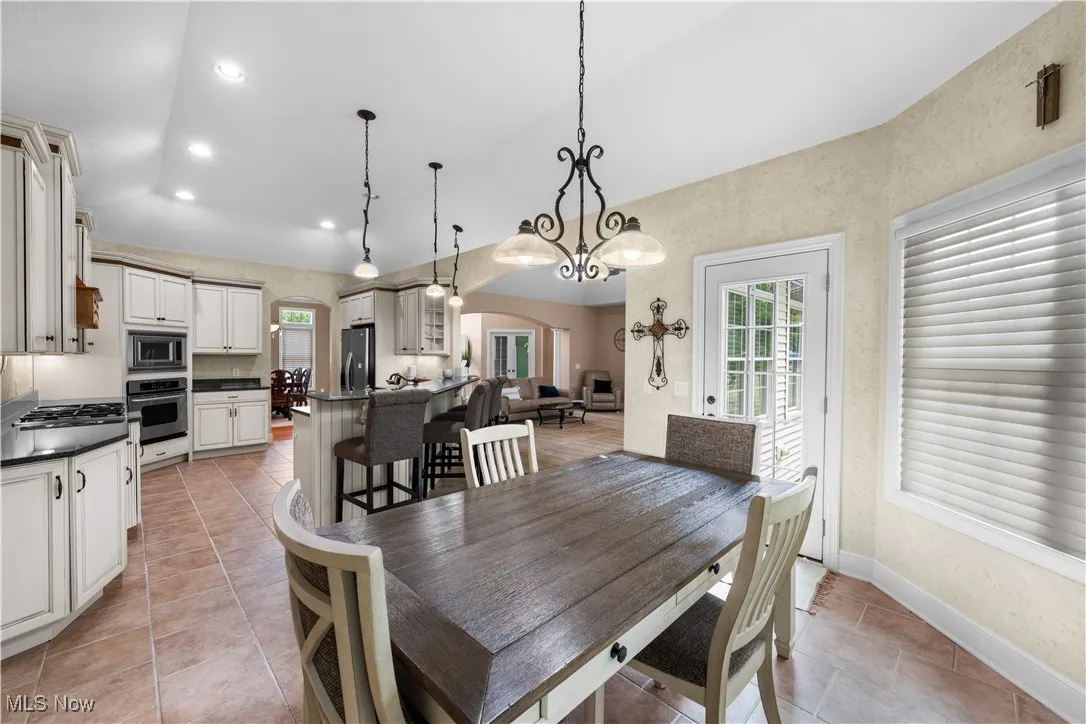 Dining room featuring arched walkways, recessed lighting, light tile patterned flooring, and lofted ceiling