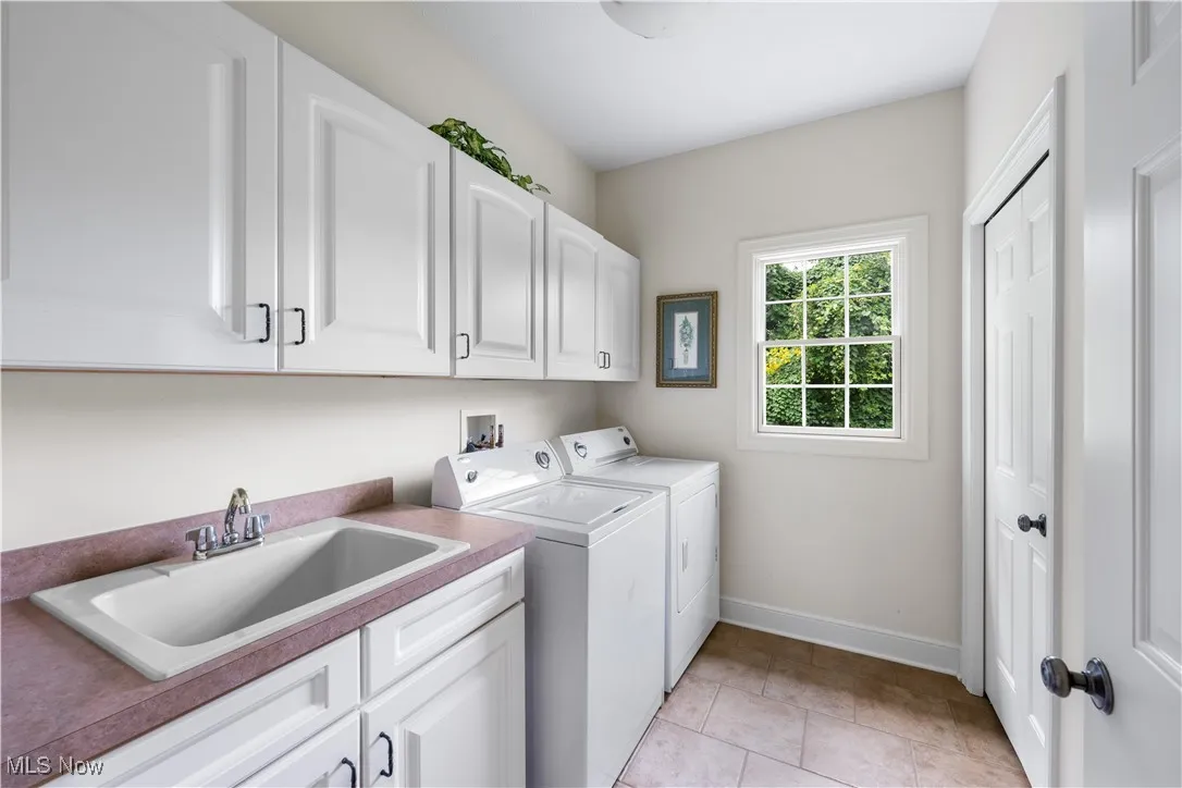 Washroom featuring cabinet space, separate washer and dryer, and light tile patterned floors