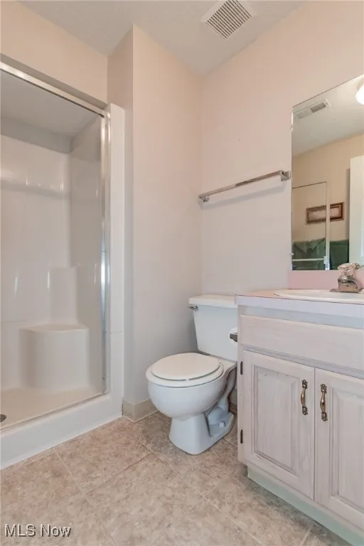 Bathroom featuring vanity, a shower stall, a textured ceiling, and light tile patterned flooring