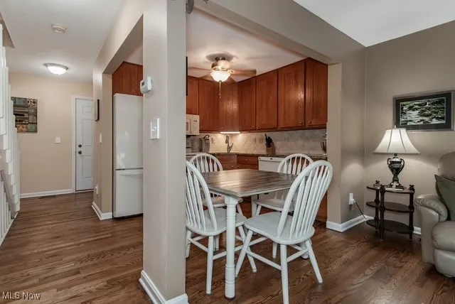Dining area and kitchen with dark wood finished floors and a ceiling fan