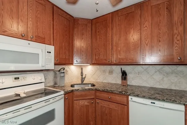 Kitchen featuring white appliances, brown cabinetry, and backsplash