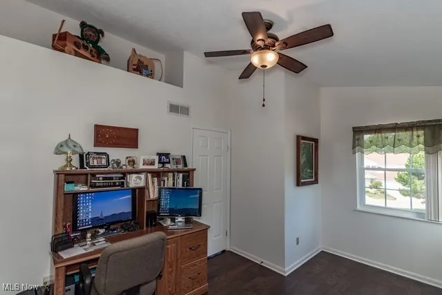 Home office with dark wood-style flooring, a ceiling fan, and vaulted ceiling