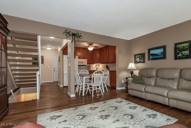 Living room with dark wood-style flooring and open stairs