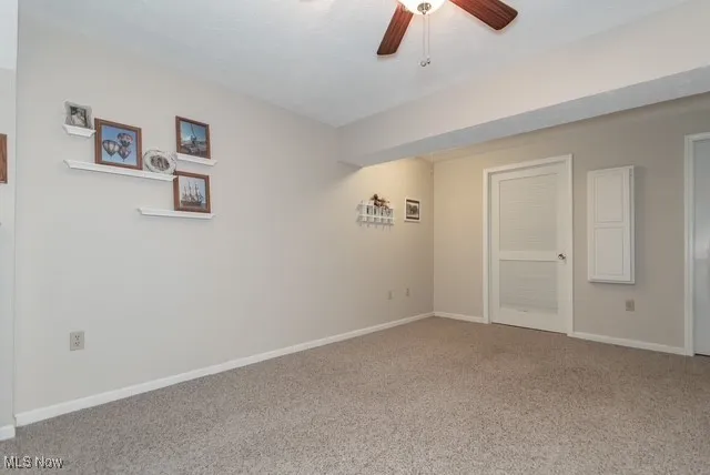 Carpeted empty room featuring baseboards and ceiling fan