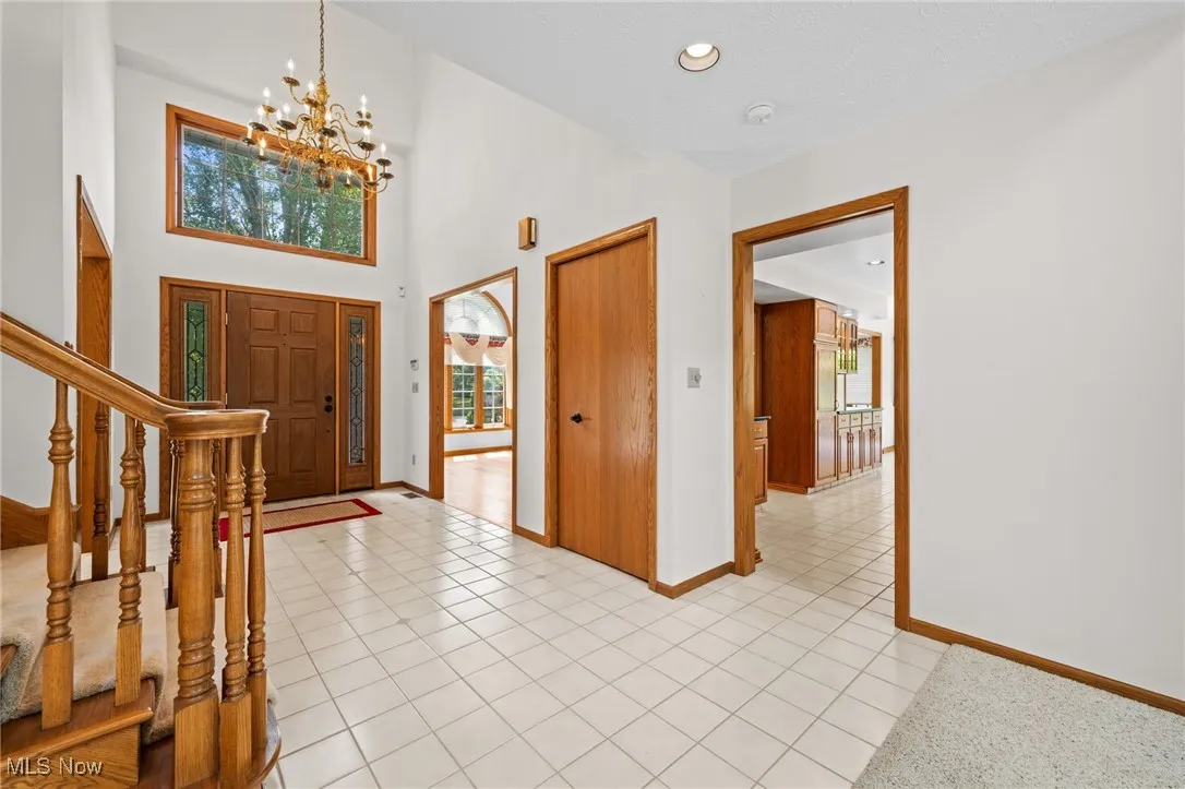 Entrance foyer with light tile patterned floors, a chandelier, stairs, a high ceiling, and recessed lighting