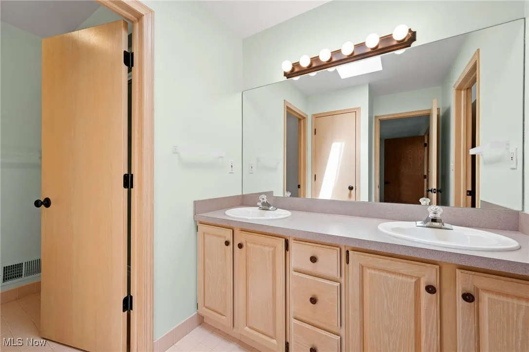 Full bath featuring light tile patterned flooring and a skylight