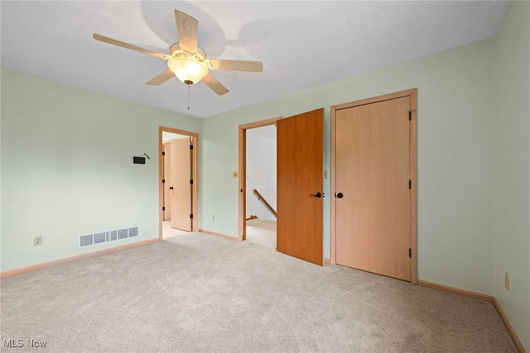 Unfurnished bedroom with carpet, ceiling fan, and a closet