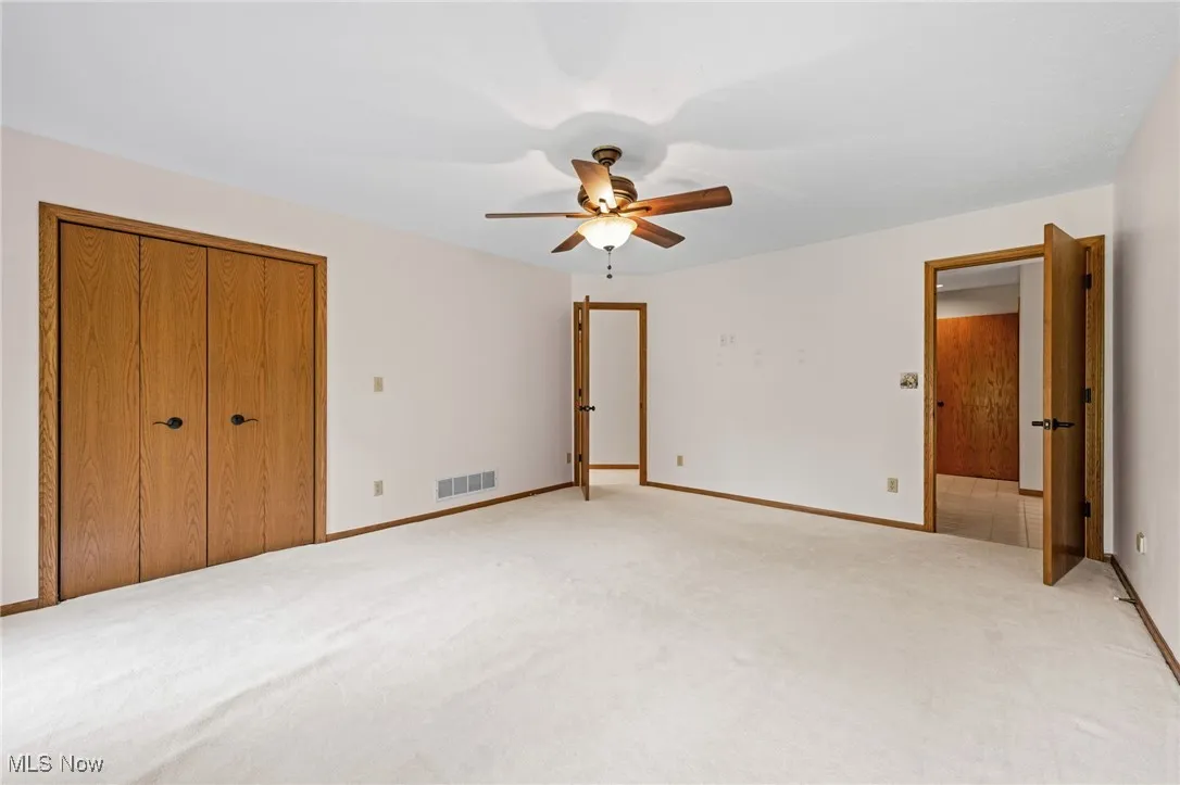 Unfurnished first floor primary bedroom featuring carpet, a closet, and a ceiling fan