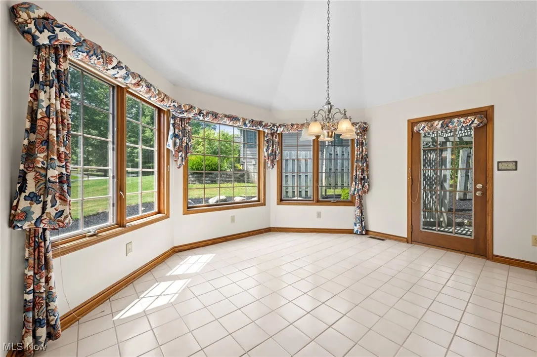 Unfurnished breakfast nook with vaulted ceiling, healthy amount of natural light, light tile patterned floors, and a chandelier